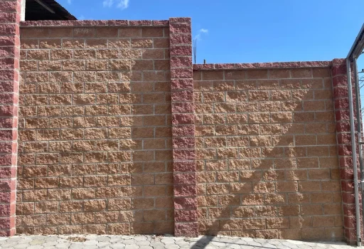 Fachada de barda perimetral con block split texturizado a dos colores y piso de adoquines de concreto.