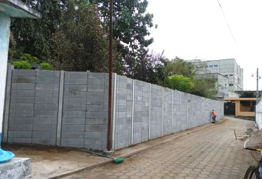 Instalación de barda prefabricada de concreto con paneles y postes reforzados para delimitación de terrenos.